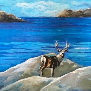 a rocky mountain elk in front of a vivid blue lake