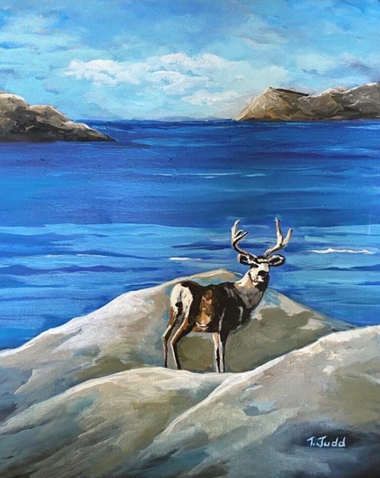 a rocky mountain elk in front of a vivid blue lake